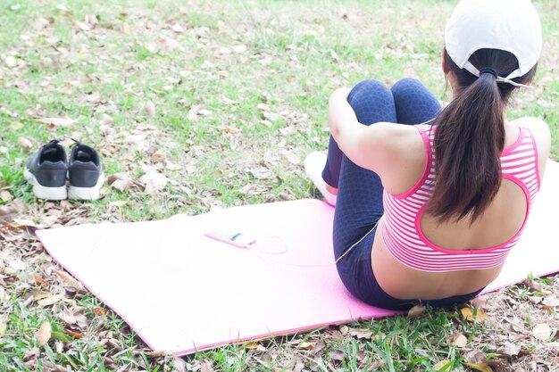 Vista posterior de la mujer en sujetador deportivo sentado y escuchando música, estilo de vida feliz y saludable c