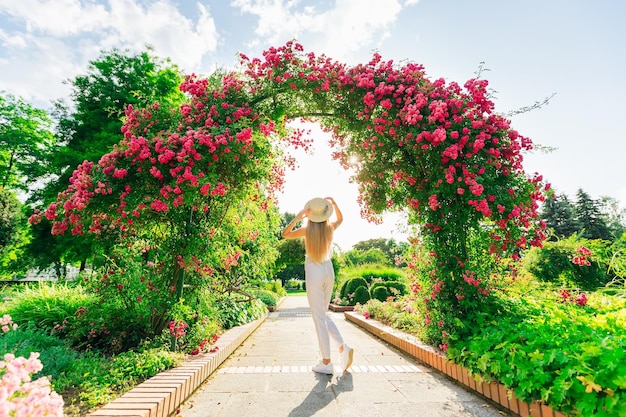 Vista posterior de una niña con navegante cerca de los arcos con rosas rosadas.