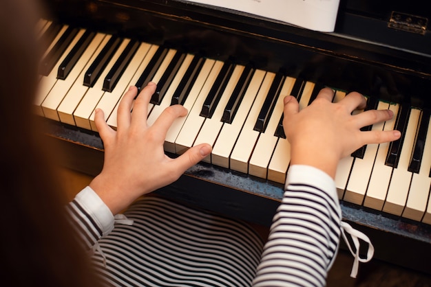 Vista posterior de una niña pianista tocando el piano