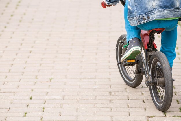 Vista posterior de un niño montando una bicicleta pequeña en el parque Niño en bicicleta en una carretera asfaltada