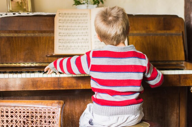 Vista posterior del niño tocando el piano clásico