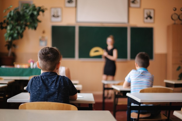 Vista posterior de los niños sentados en la sala de clase y estudiando la escuela primaria