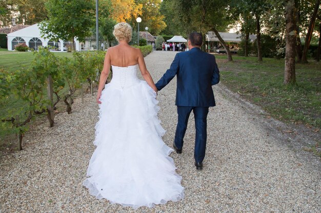 Vista posterior de la novia y el novio tomados de la mano van a la celebración de la boda