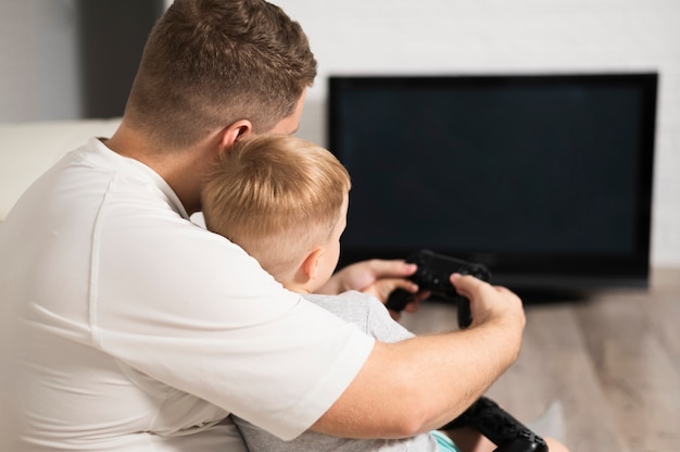 Vista posterior padre e hijo jugando videojuegos