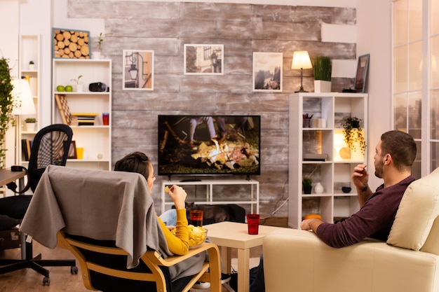 Vista posterior de la pareja en la sala de estar viendo una película en la televisión mientras come comida para llevar