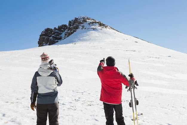 Vista posterior de una pareja con tablas de esquí de pie sobre la nieve