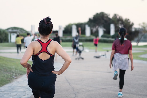 Vista posterior de personas maduras y saludables que bailan aeróbicos en el parque de la ciudad por la noche después del trabajo para relajarse y tener una vida saludable. Deportes y Recreación