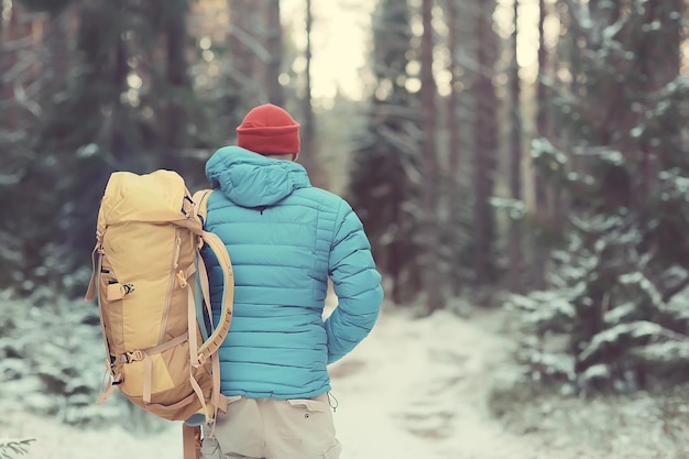 vista posterior de un turista con mochila haciendo senderismo en invierno en Noruega / un hombre que lleva una mochila en un paisaje invernal noruego.