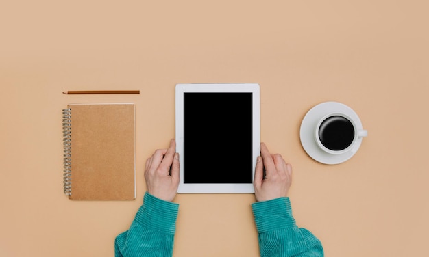 Vista de pov en manos femeninas y tableta junto al cuaderno y taza de café