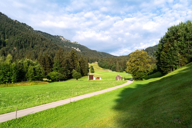 Vista de los prados alpinos bien cuidados con dependencias y la carretera que se extiende en la distancia.