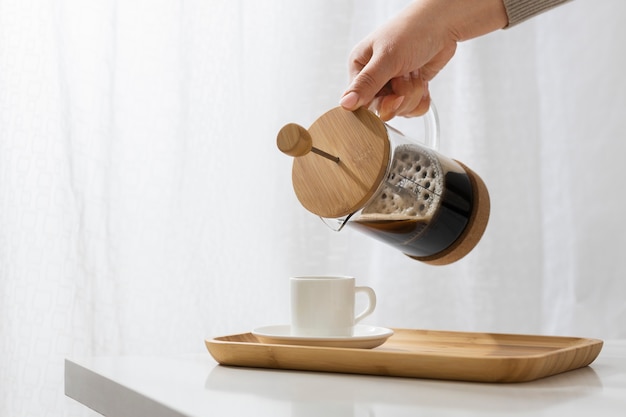 Foto vista de la prensa francesa para café con taza de madera.