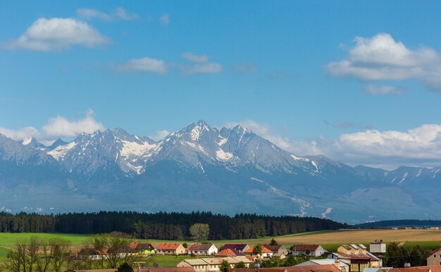 Vista de primavera de High Tatras con nieve en la ladera de la montaña y la aldea (Eslovaquia)