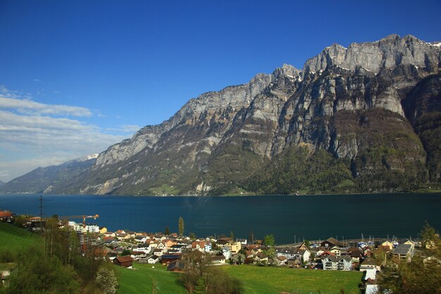 Vista de primavera del lago con la montaña y la ciudad en el fondo