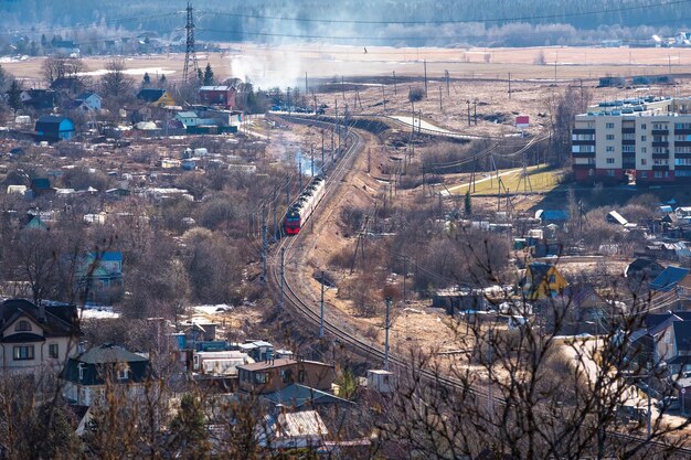 Vista de primavera rústica con un tren El tren rojo sale de la estación del pueblo en la vista de distancia de primavera