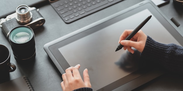 Foto vista de primer plano del diseñador femenino dibujo en tableta en lugar de trabajo elegante y oscuro