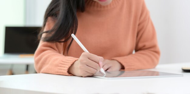 Vista de primer plano de joven mujer trabajando en su proyecto con tableta