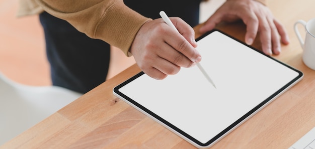 Vista de primer plano de joven trabajando en su proyecto con tableta de pantalla en blanco