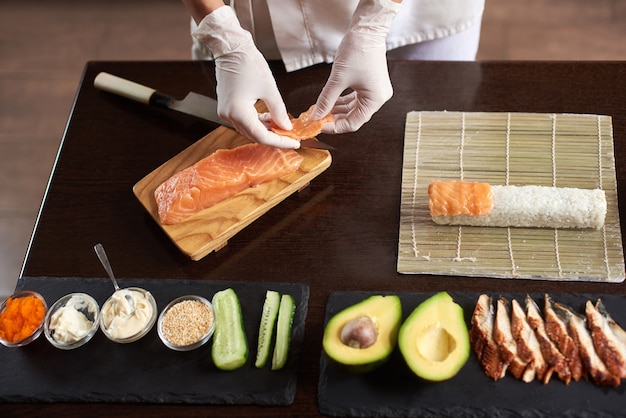 Vista de primer plano de las manos del chef preparando comida japonesa