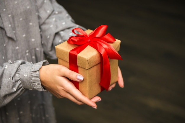 Vista de primer plano, mujer en ropa gris tiene una caja de regalo