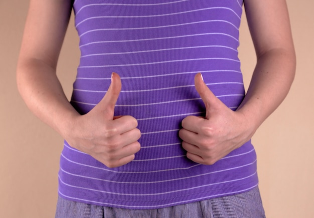 Una vista de primer plano del vientre de una mujer embarazada con una camiseta violeta que muestra un signo similar.