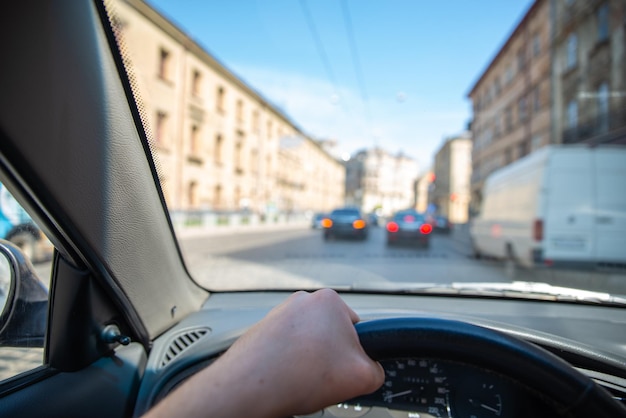 Vista en primera persona hombre conduciendo coche por calles de la ciudad tráfico urbano