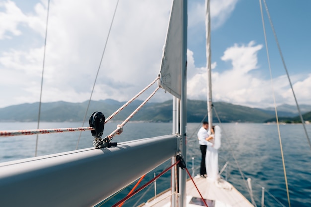 Vista desde la proa de un yate de vela para los recién casados en la popa de un velero con el telón de fondo