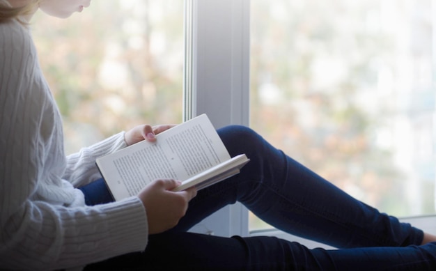 Vista próxima da mulher de suéter de lã branca segurando um livro Espaço livre para sua maquete do fundo do conceito de livro de leitura