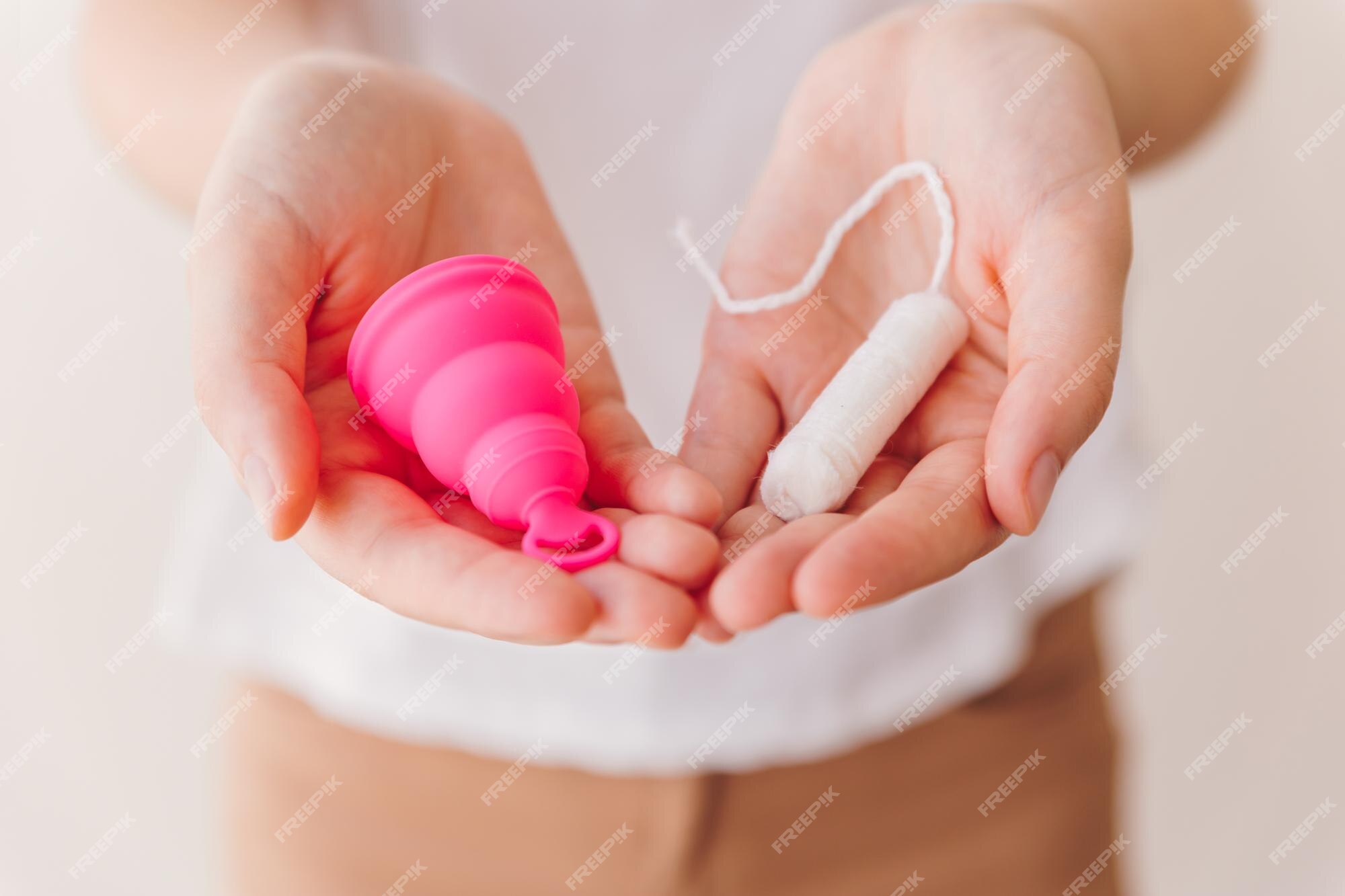 mão de uma mulher segurando o copo menstrual rosa isolado no fundo branco.  mulher moderna alternativa eco ginecológica higiene no período de  menstruação. recipiente para sangue na mão da menina. 5427428 Foto