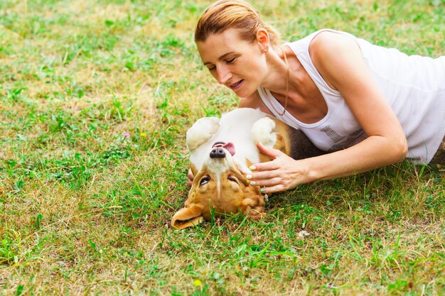 Vista próxima do cachorro Beagle engraçado com a língua para fora e dona da mulher, ambos deitados na grama verde. Conceito de melhores amigos de animais