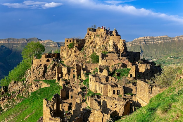 Vista del pueblo abandonado de Gamsutl en la cima de una montaña en Daguestán con turistas entre las ruinas