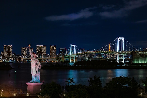 Foto vista del puente arco iris y la estatua de la libertad en odaiba, japón por la noche