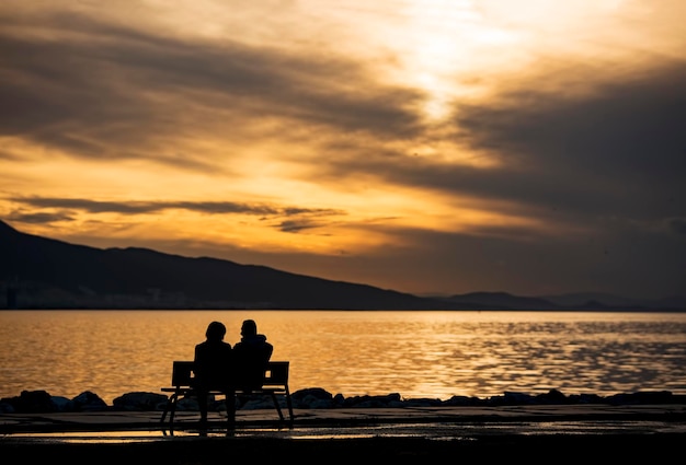 Vista de la puesta de sol en el banco sentado de la pareja de silueta.