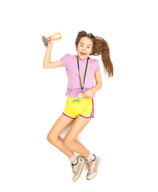 Vista desde el punto más alto de la niña animando saltando alto con medalla de oro y copa