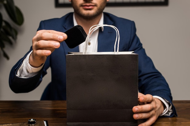 Foto vista recortada de la caja de sujeción del tasador de joyas cerca de la bolsa de papel en la mesa