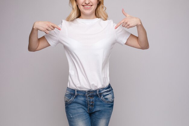 Vista recortada da morena em pé na camisa branca e calça jeans