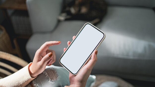 Vista recortada das mãos femininas segurando o telefone celular em branco com cópia em branco da tela do telefone inteligente com o conceito de tecnologia