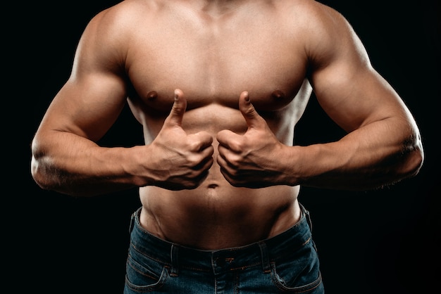 Vista recortada de fisiculturista sexy com torso muscular, mostrando os polegares para cima isolado no preto