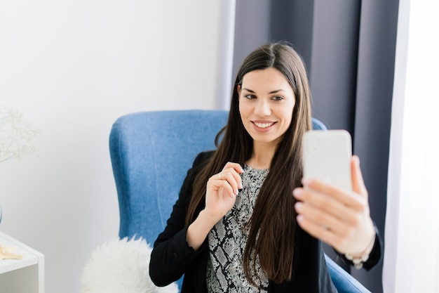 Vista recortada de mãos femininas segurando um telefone inteligente. Mulher com telefone celular em casa. Foco seletivo