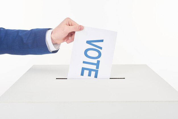 Foto vista recortada de um homem colocando um cartão com voto em uma caixa isolada em branco