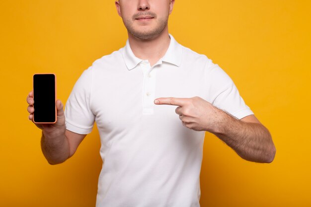 Vista recortada del hombre apuntando al teléfono inteligente en amarillo