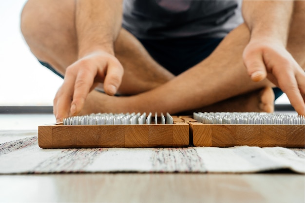 Vista recortada del hombre que ejercita yoga meditando y sentado en el suelo cerca del tablero de sadhu