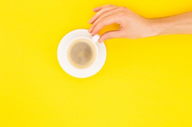 Vista recortada del hombre que sostiene la taza de café aislado en amarillo