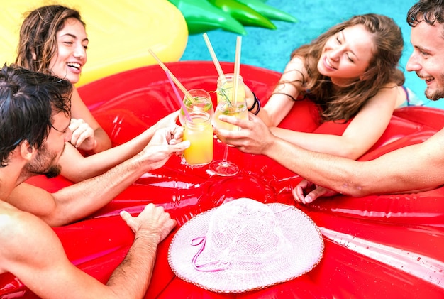 Vista recortada de jóvenes bebiendo cócteles de frutas en la fiesta de la piscina