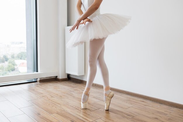 Vista recortada de las lagas de una hermosa y graciosa bailarina en vestido de cisne blanco