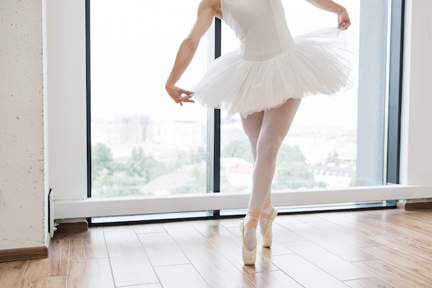 Vista recortada de las lagas de una hermosa y graciosa bailarina en vestido de cisne blanco