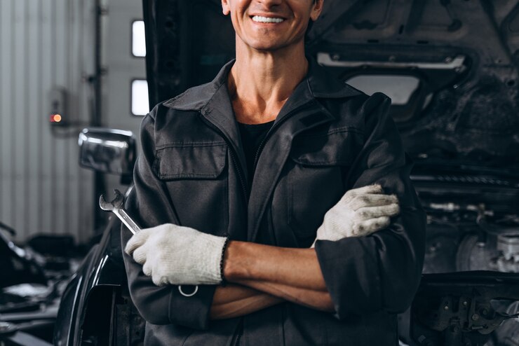 Foto vista recortada del mecánico de automóviles de pie cerca del automóvil abierto al aire libre y sosteniendo la llave. concepto de reparación de automóviles