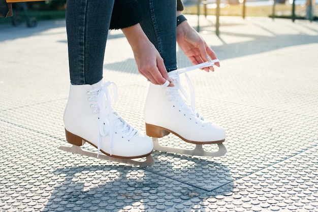 Vista recortada de mujer atando cordones de zapatos en pancarta de patines de hielo