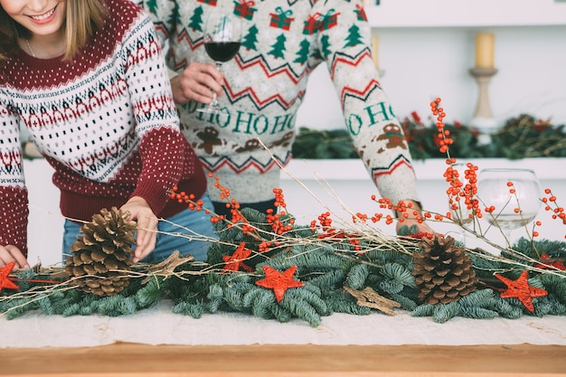 Vista recortada de una mujer joven está decorando una mesa con adornos navideños