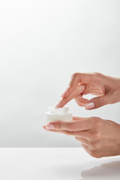 Foto vista recortada de mujer sosteniendo tarro con crema en las manos