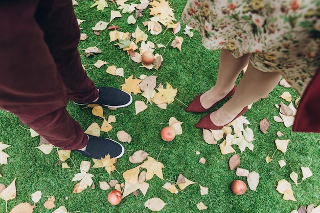 Vista recortada de la pareja hombre y mujer enamorados de pie al aire libre con hojas de otoño en el fondo. Concepto de estilo de vida y relaciones